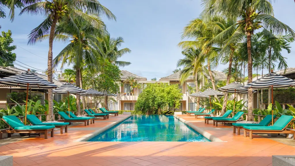Long outdoor swimming pool lined with loungers and palms at Signature Phuket Resort