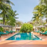 Long outdoor swimming pool lined with loungers and palms at Signature Phuket Resort