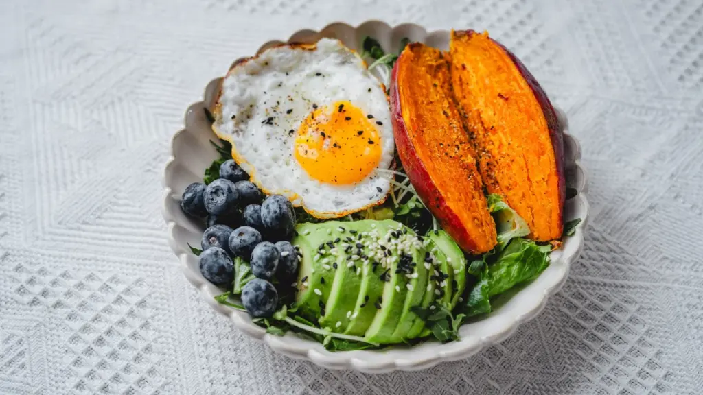Grain bowl with egg, avocado, sweet potato and blueberries for a practical post-training meal