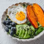 Grain bowl with egg, avocado, sweet potato and blueberries for a practical post-training meal