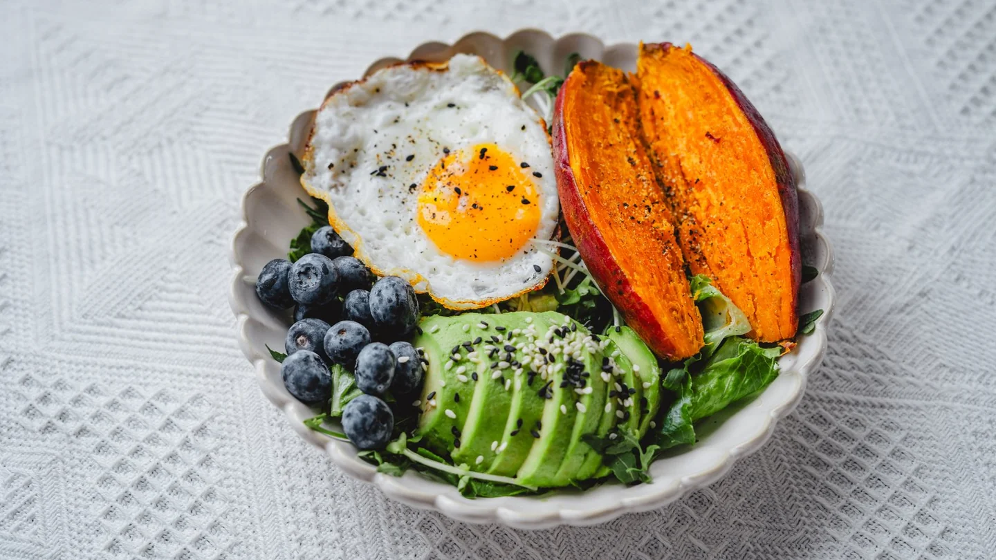 Grain bowl with egg, avocado, sweet potato and blueberries for a practical post-training meal